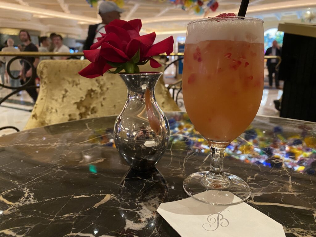 Cocktail on marble table next to vase of red flowers