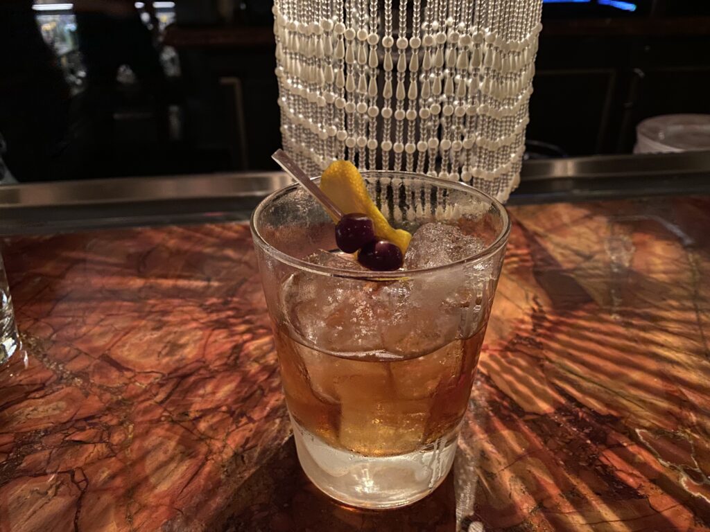 Old fashioned cocktail in front of a lamp.